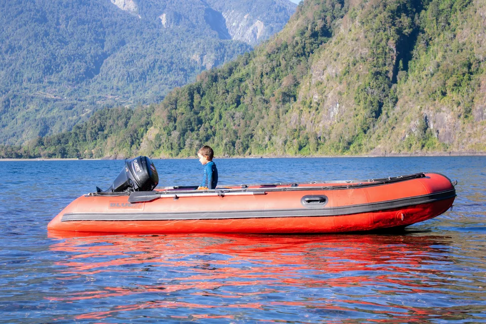 Bote rojo frente a montañas junto al lago