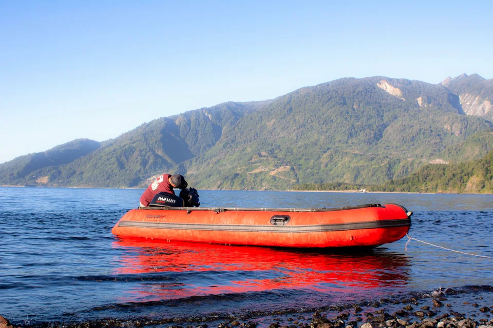 Bote rojo en un lago rodeado de montañas