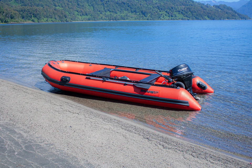 Bote rojo frente a un bosque junto al lago
