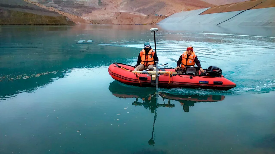 Bote rojo sobre aguas turquesa frente a montañas